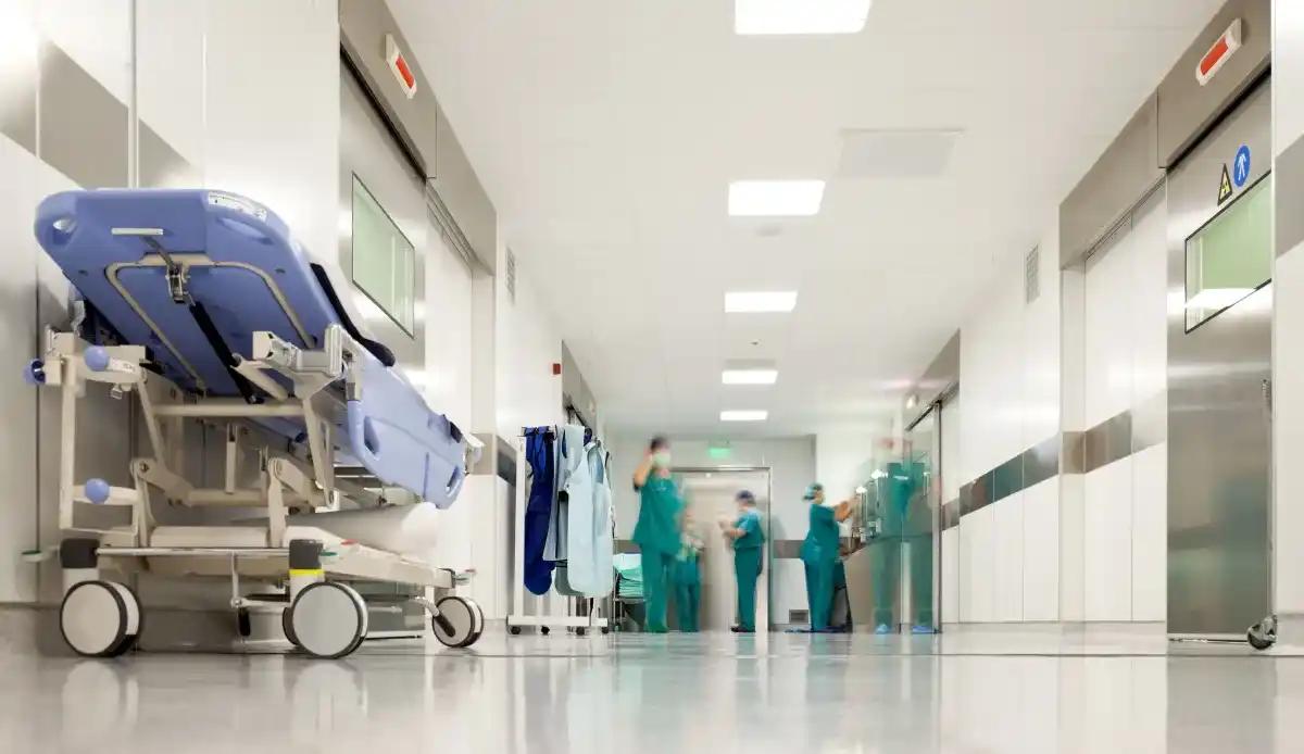 A hospital hallway with a stretcher and nurses in the background