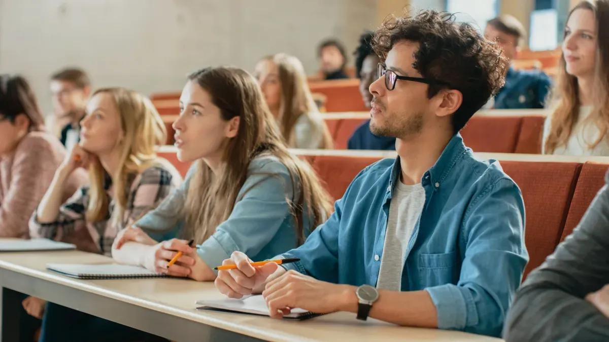 A group of students are sitting at desks in a lecture hall