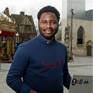 A man wearing a blue sweater with the word saxx on it