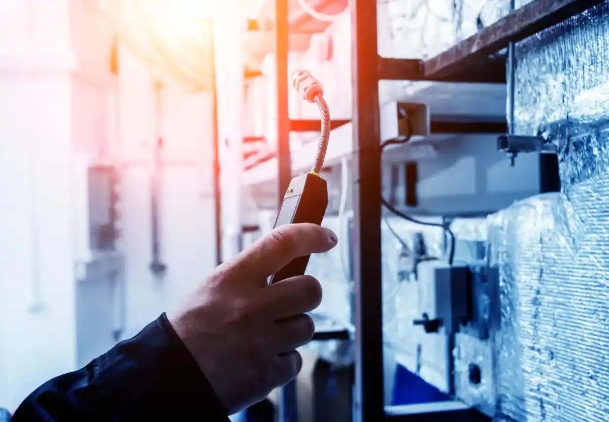 A man is holding a thermometer in his hand in a factory