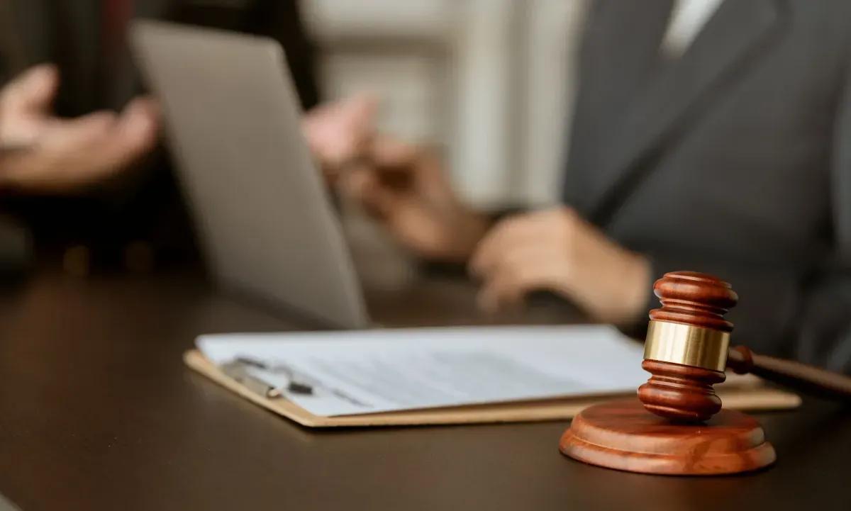 A judge is sitting at a table with a clipboard and a gavel