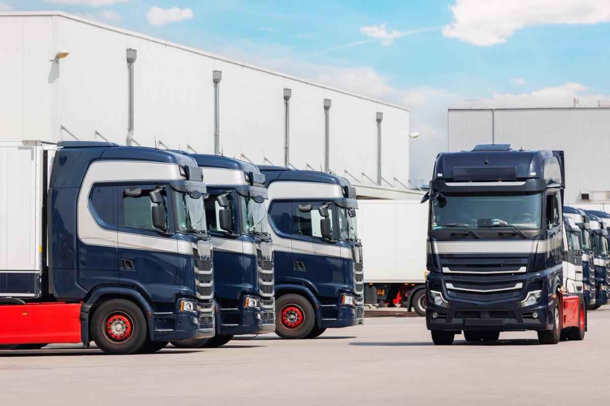 A row of semi trucks parked in front of a warehouse
