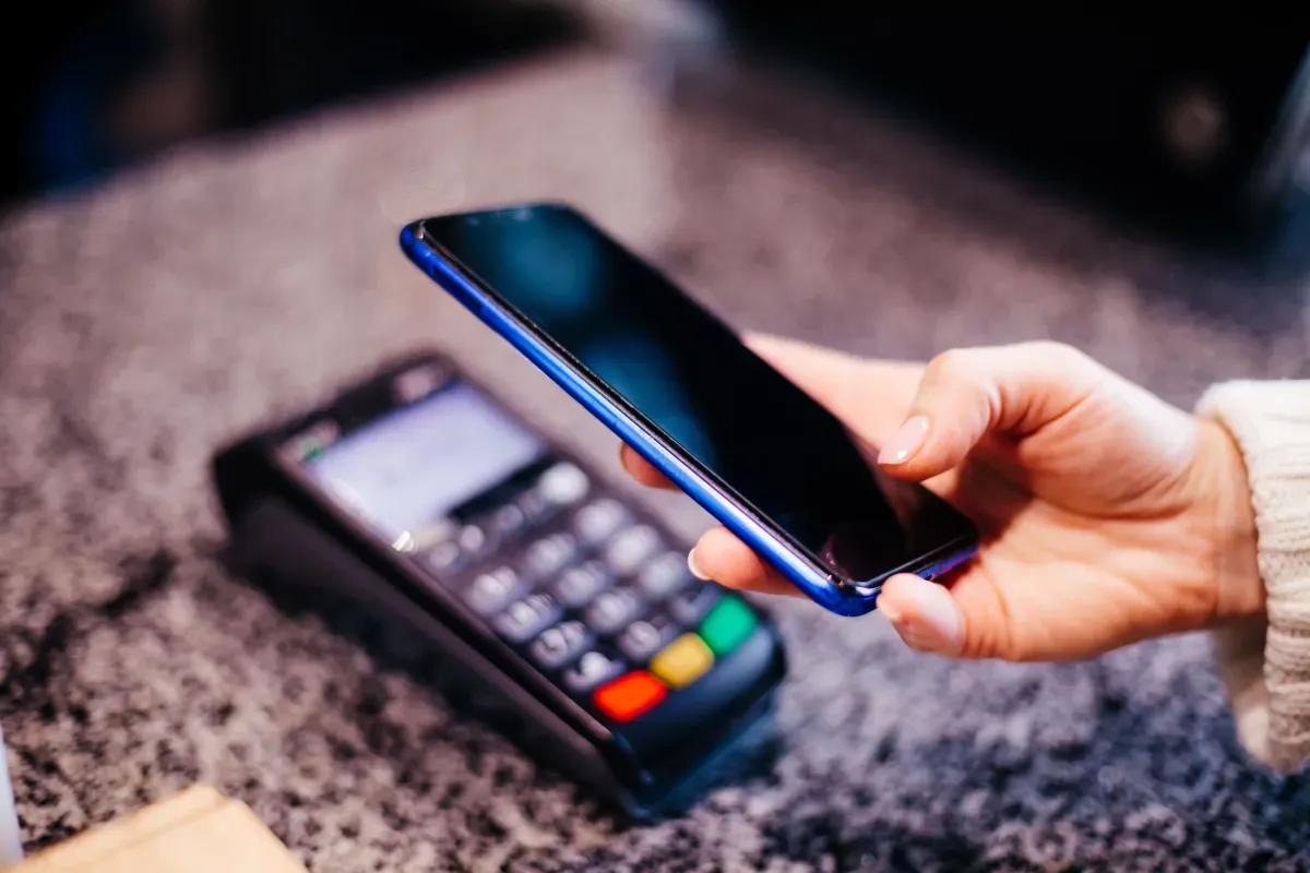 Eine person benutzt ein smartphone um mit einer kreditkarte zu bezahlen