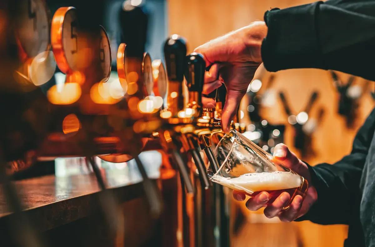 A person is pouring beer into a glass at a bar