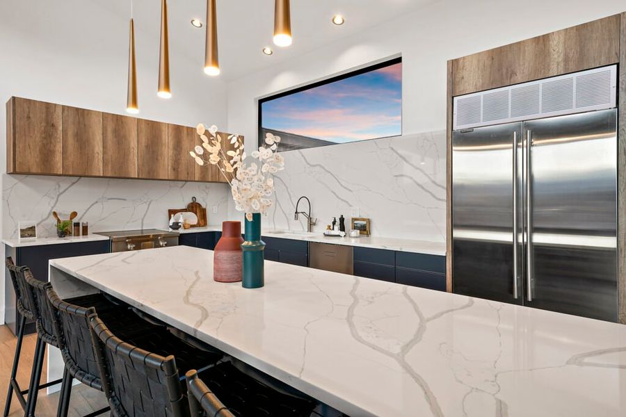 Kitchen at Icon Haus — waterfall quartz island and brass pendants in a completed Roderick Builders home