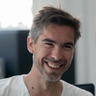 a man with a beard wearing a white shirt is smiling