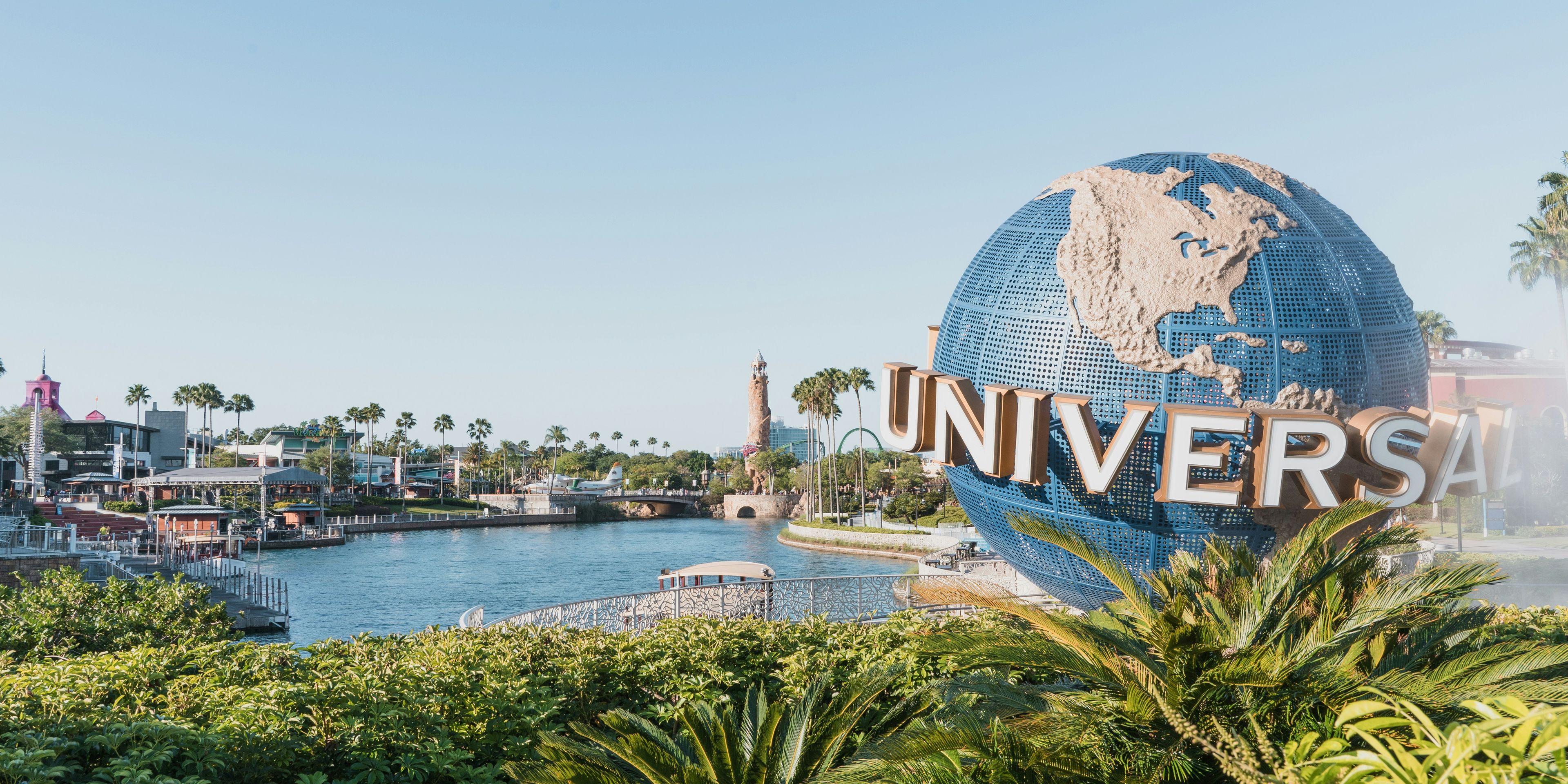 the universal studios globe is surrounded by palm trees and a body of water .