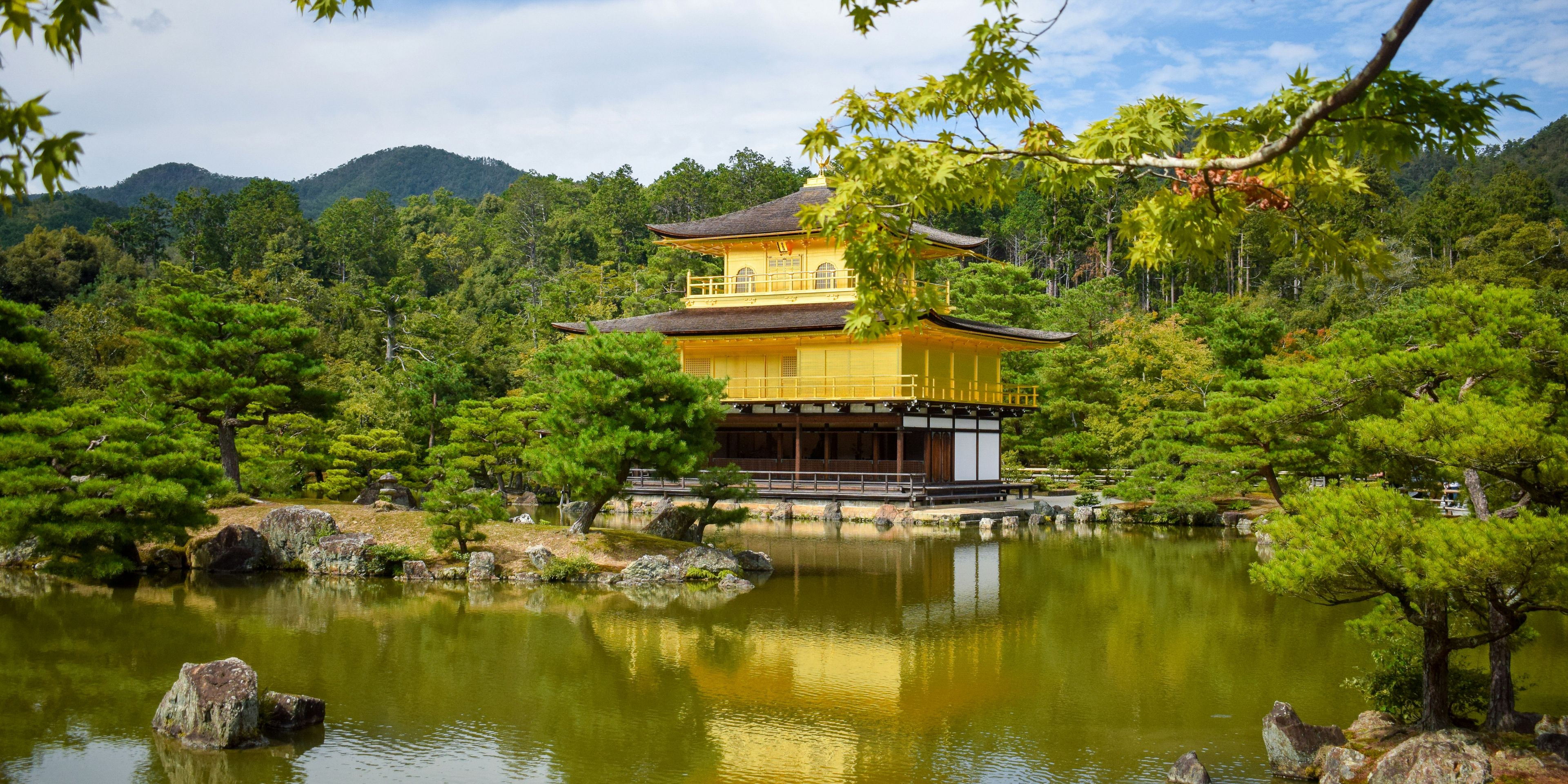 a large yellow building is sitting on top of a lake surrounded by trees .