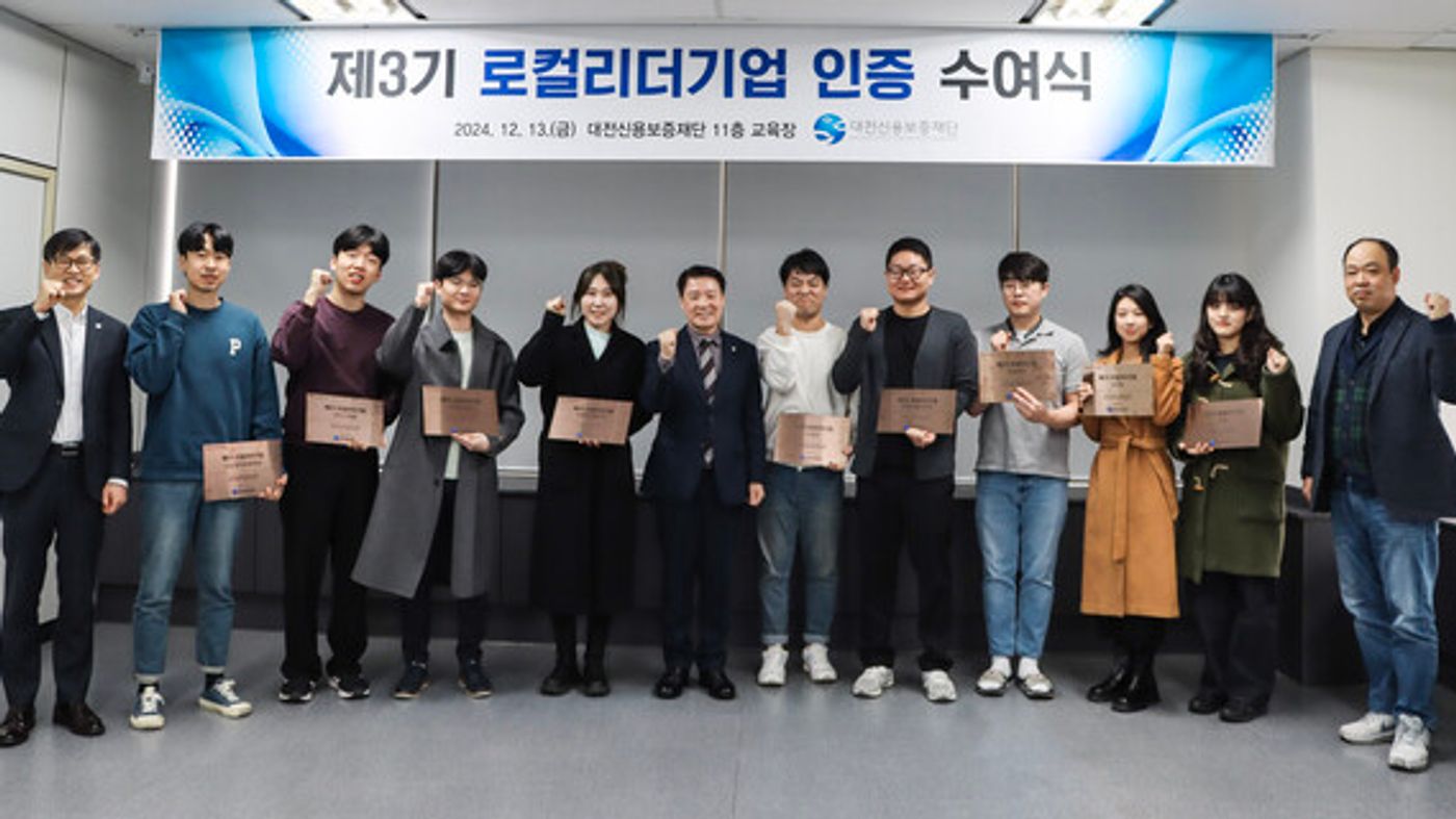 대전신용보증재단 본점에서 열린 '제3기 로컬리더기업 인증 수여식'에서 양필환 이사장과 주식회사 워코 임용묵 대표를 비롯한 12개 인증 기업 대표들이 현판을 들고 기념 촬영을 하고 있는 모습.