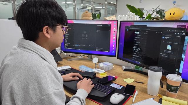사무실 책상에서 두 대의 모니터와 키보드를 사용하는 모습