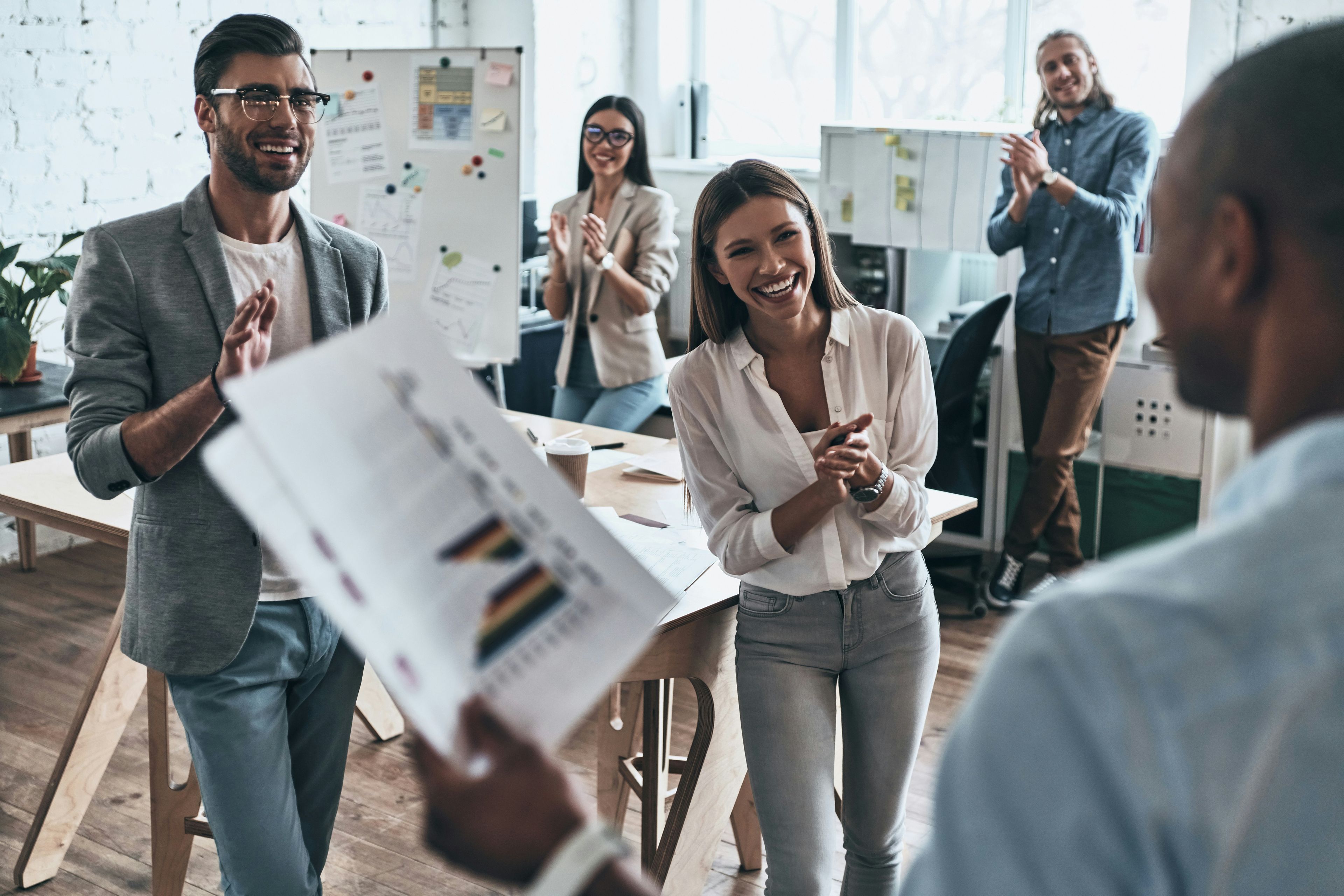 Office workers clapping and congratulating a colleague