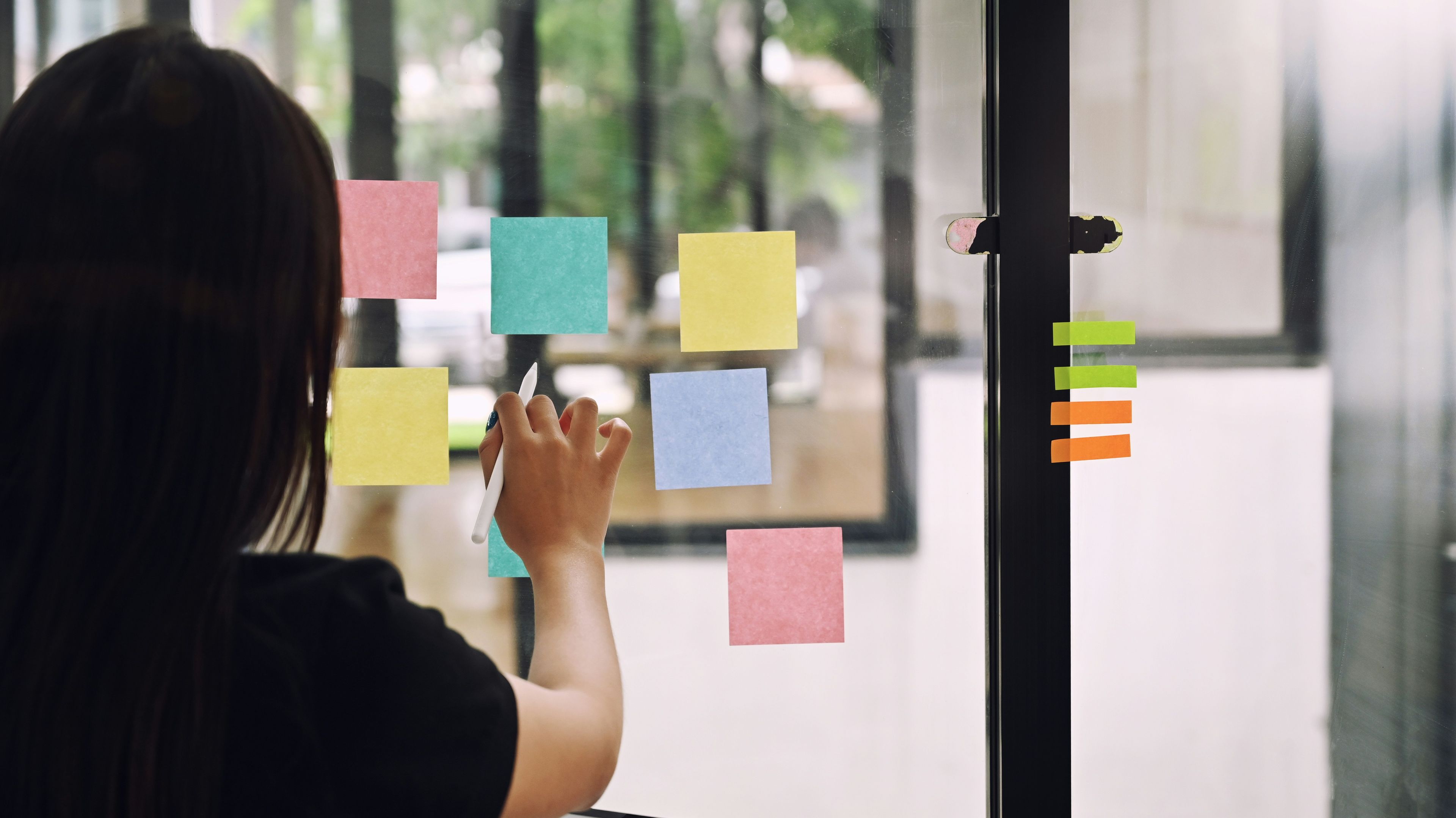 A person working with sticky notes on a window