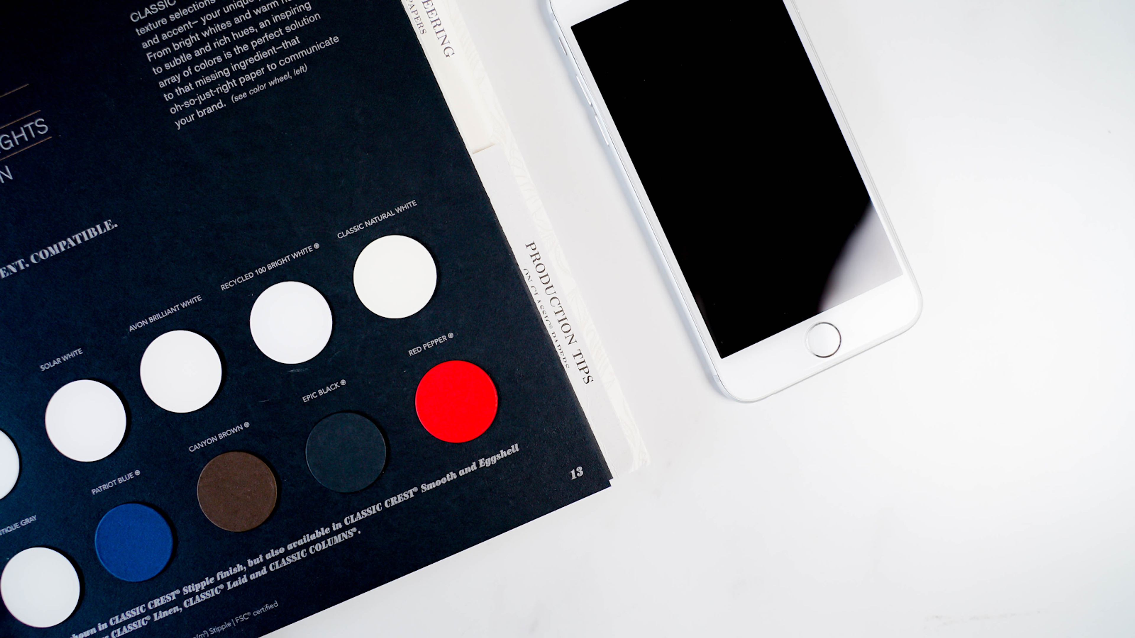 A white cell-phone and a brochure with color palette
