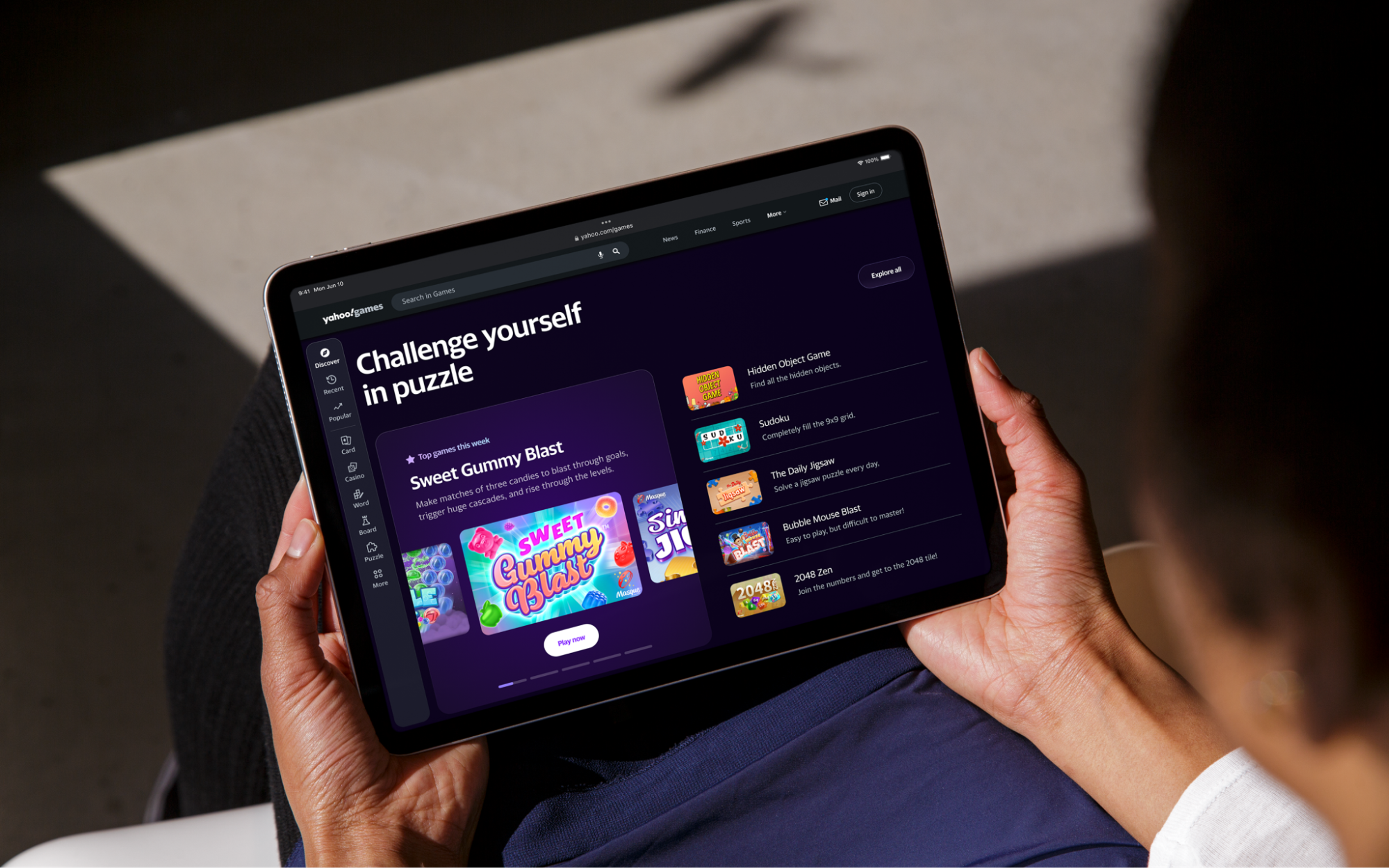 A person holding a tablet with Yahoo! Games web app opened