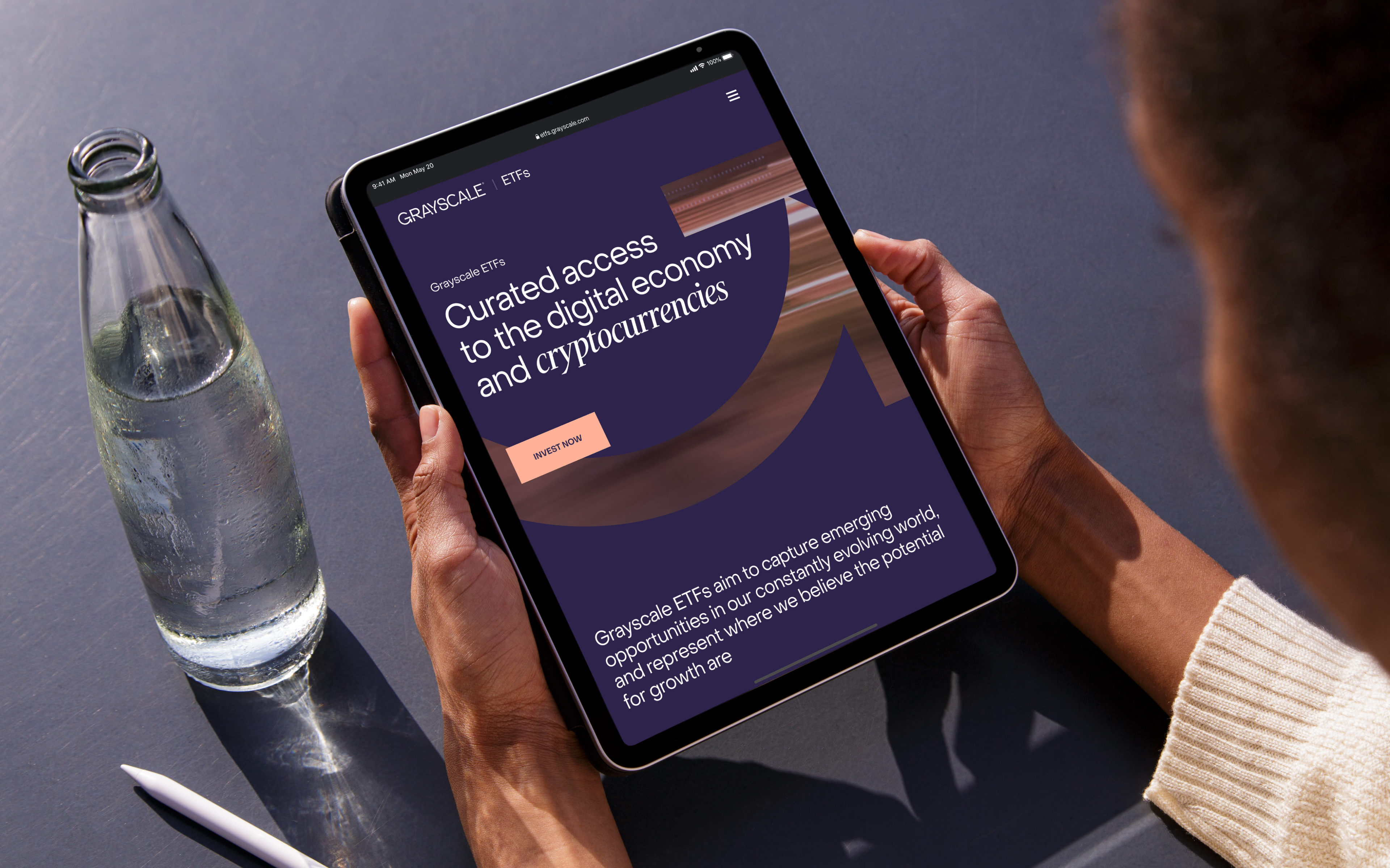 A person holding a tablet with a Grayscale website opened