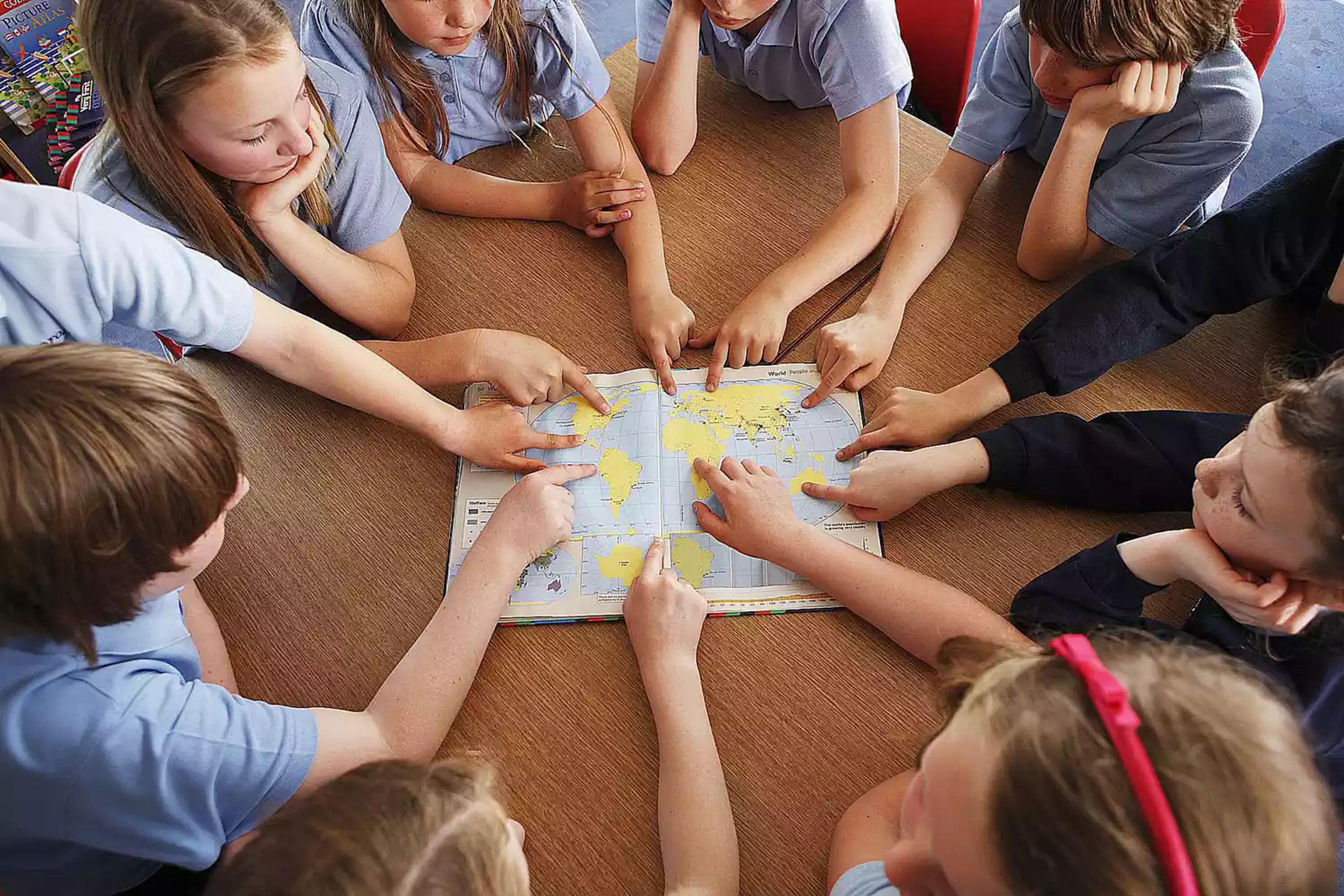 A group of children pointing to a map of the world