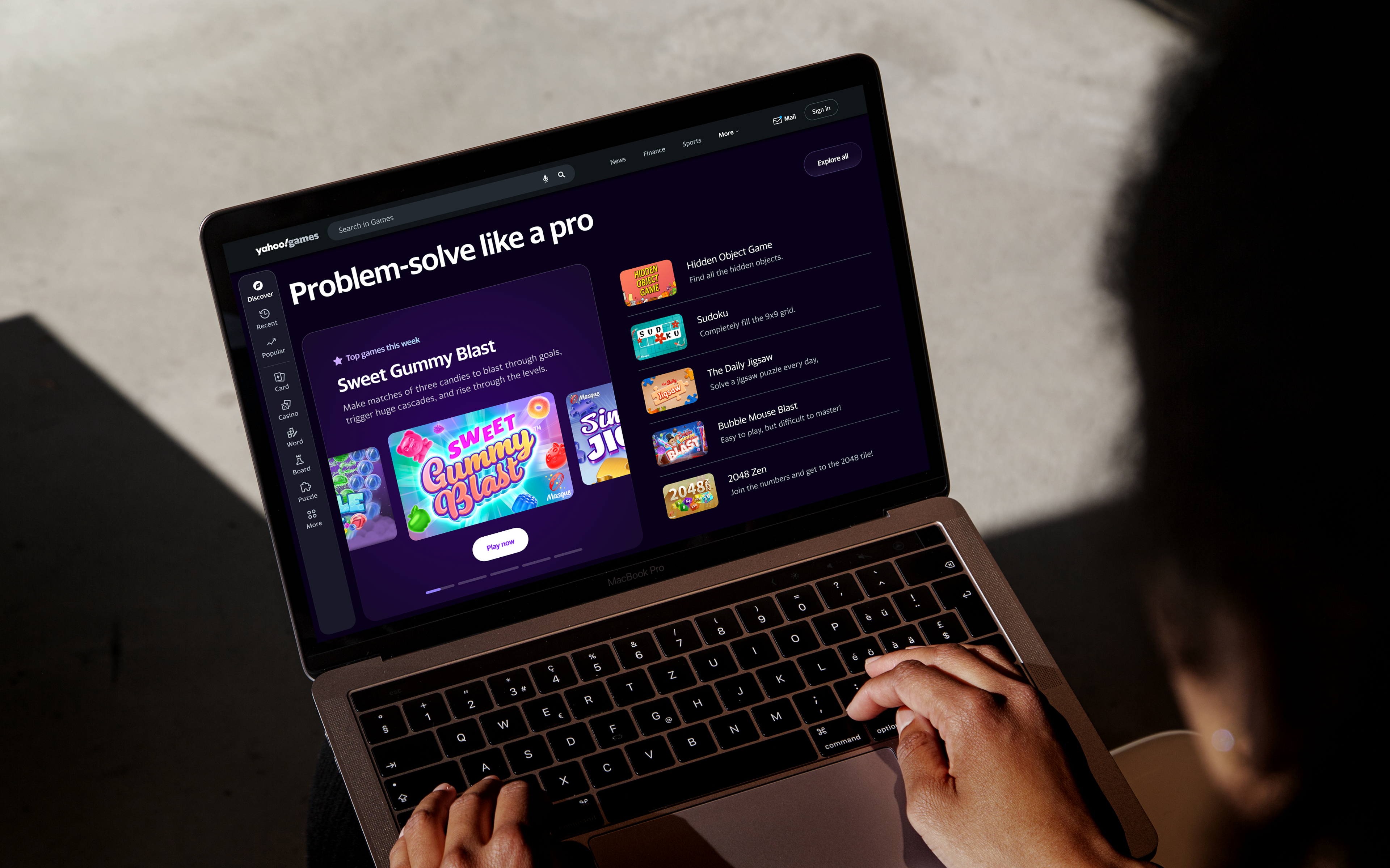 A person holding a laptop with Yahoo! Games website