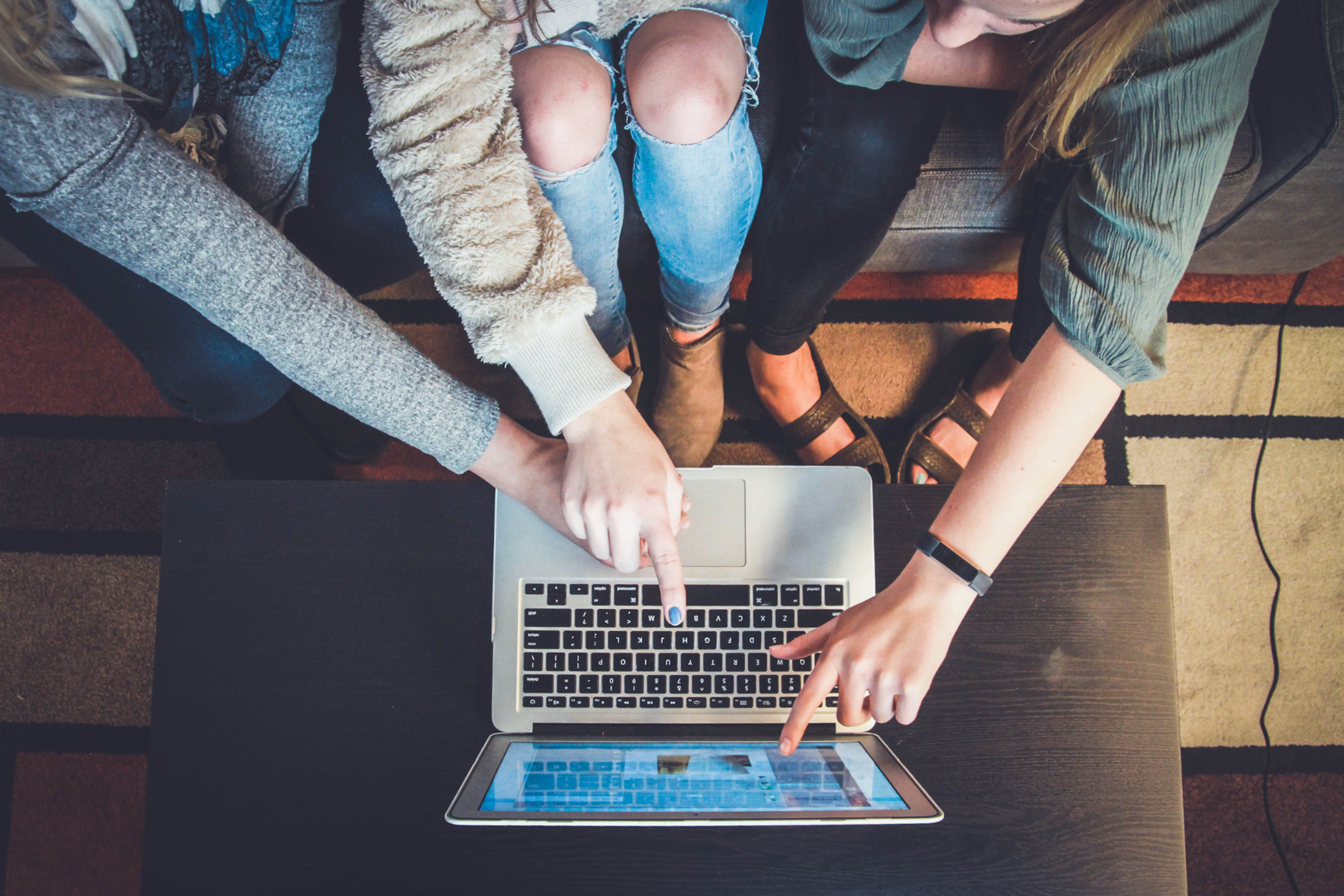 A group of girls is sitting in front of the laptop
