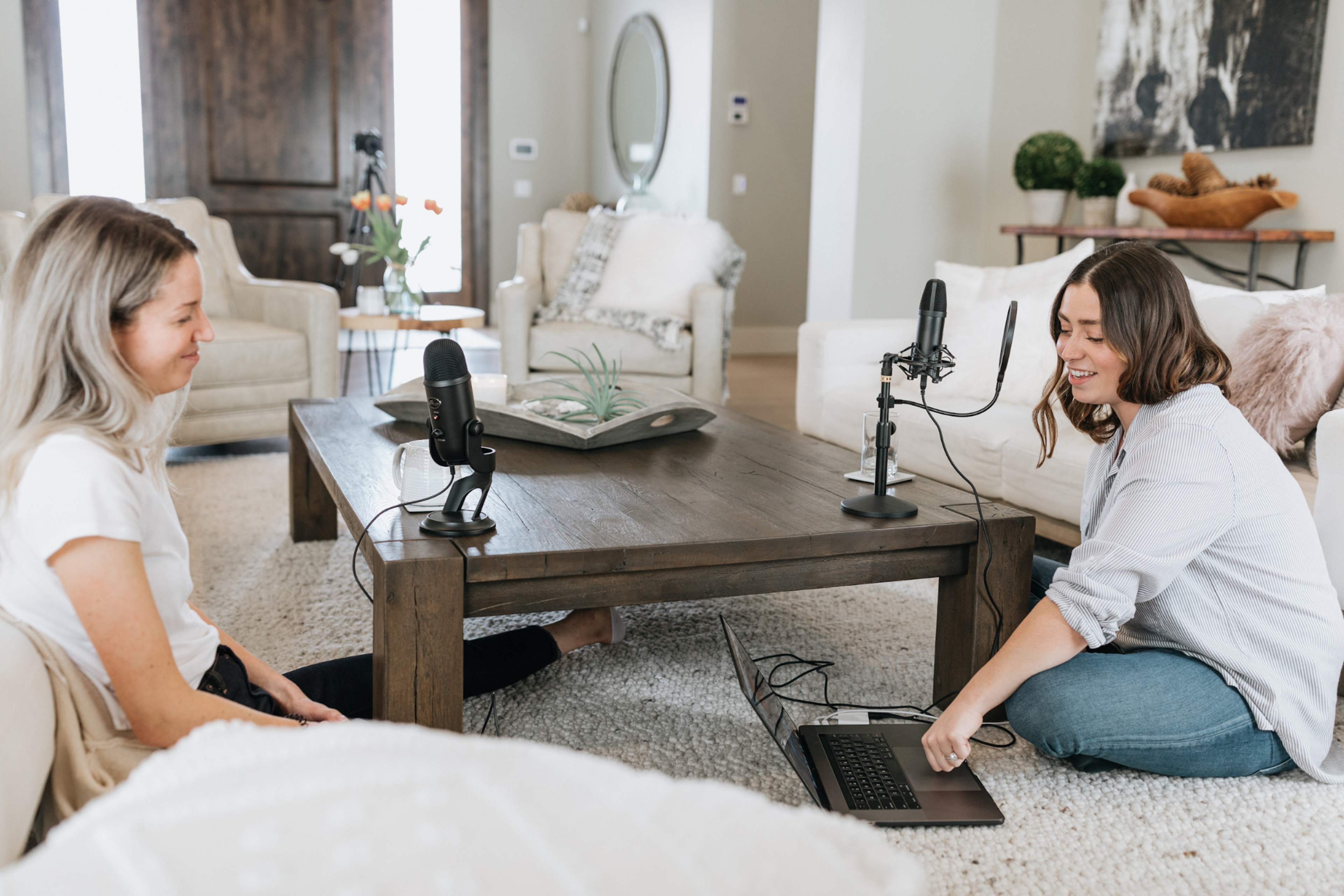 Two women recording a podcast in a cozy living room setting