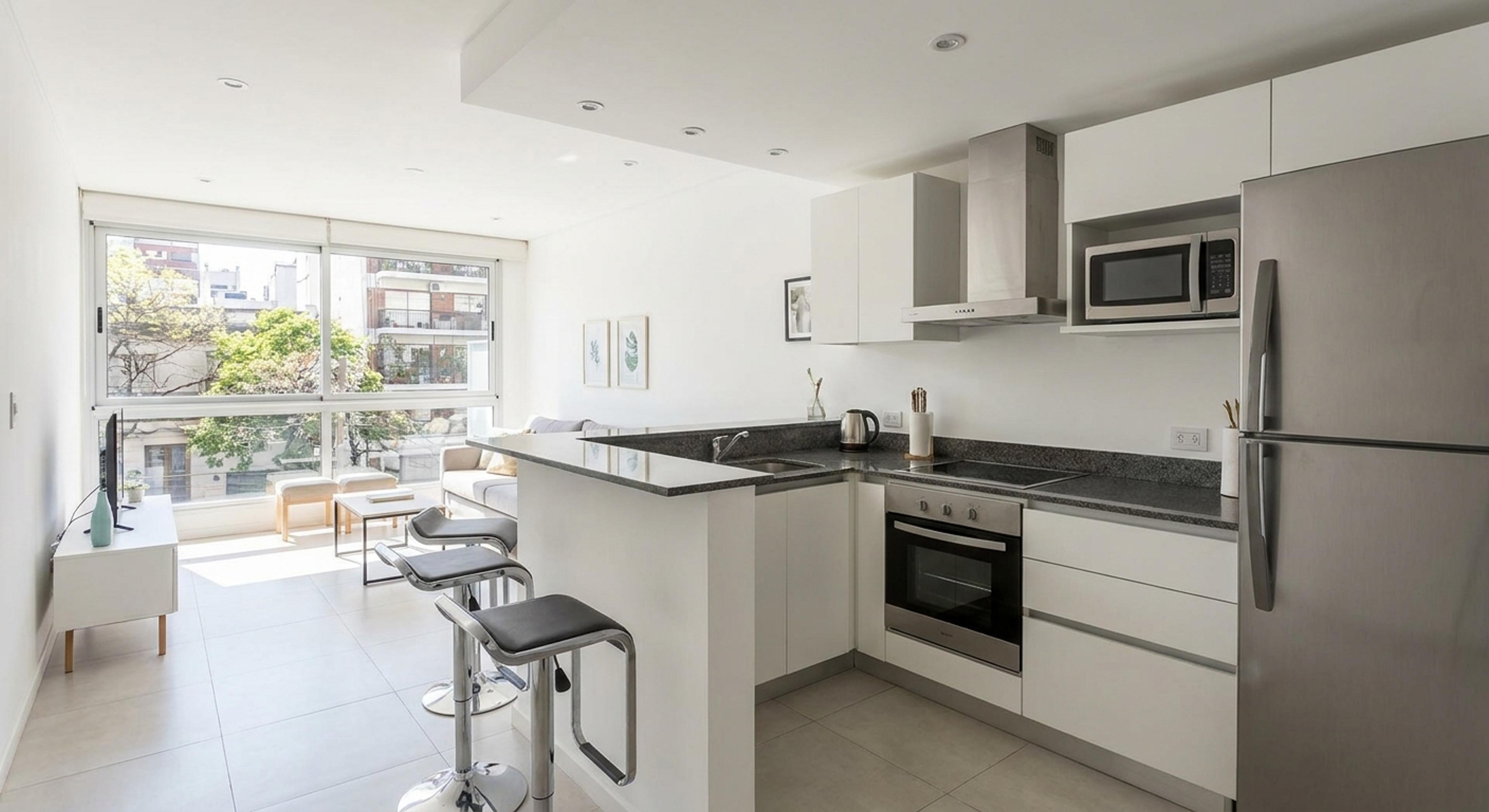 Cocina integrada moderna con barra desayunador y muebles blancos