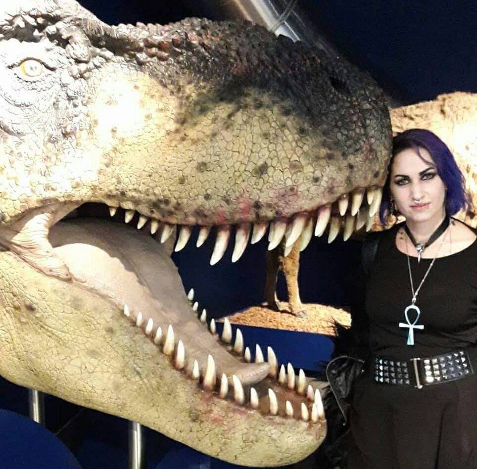 Image of a young woman next to a life size replica head of a Tyrannosaurus rex