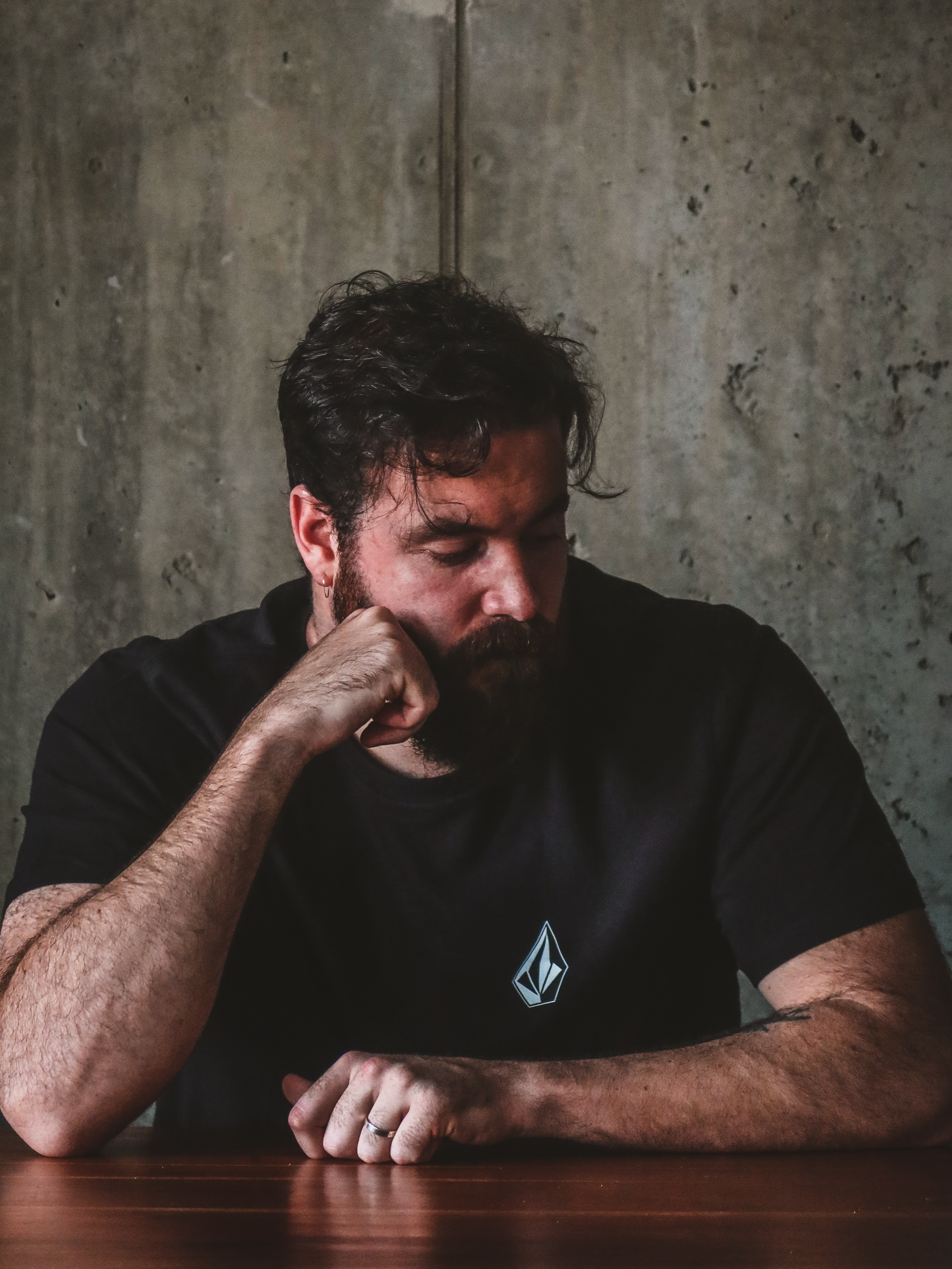 Portrait of a man sitting at a desk with a concrete wall in the background.