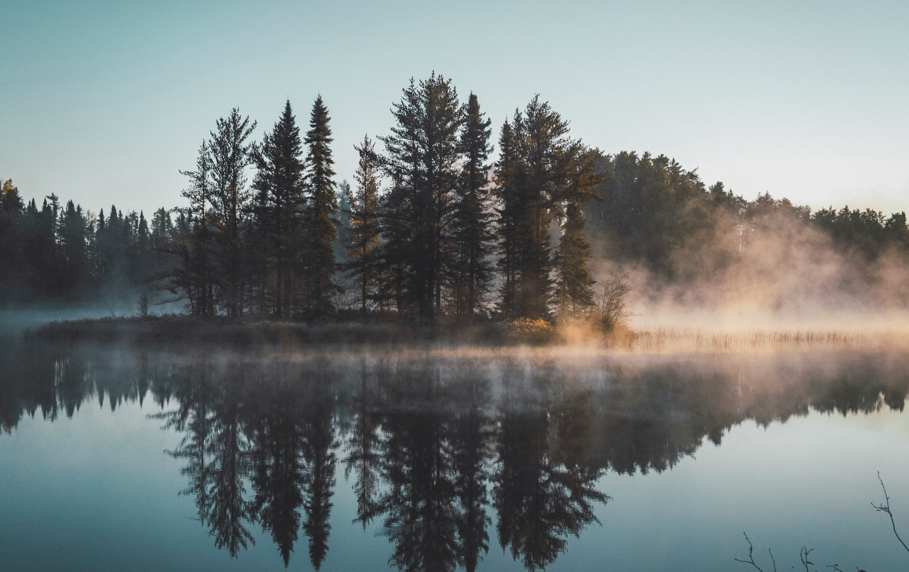 lake and landscape in blue and green tones with warm sunlight