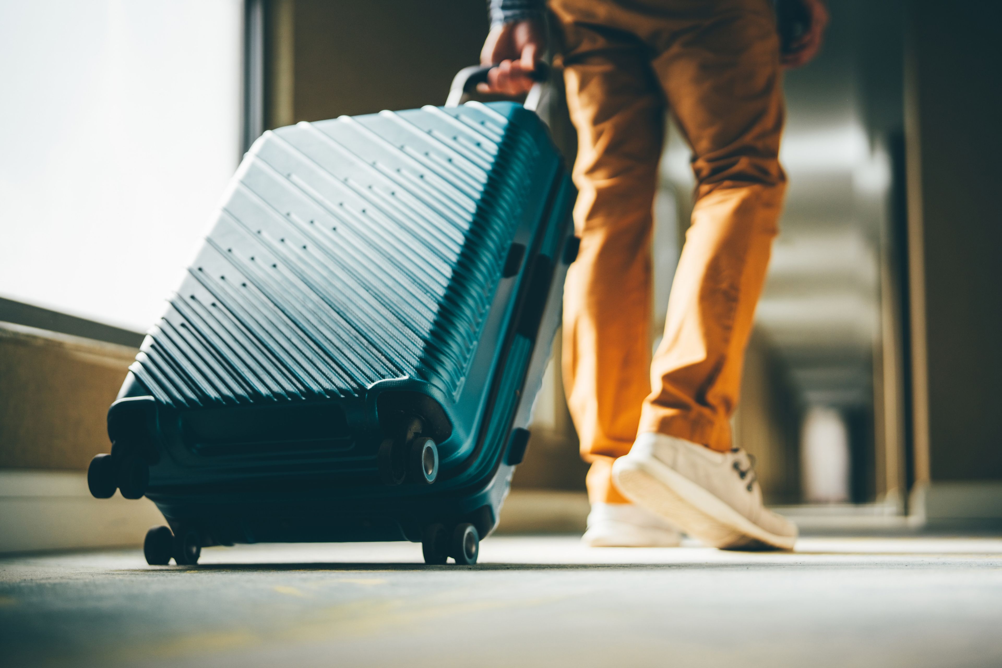 A low angle shot of a wheeled suitcase being pulled