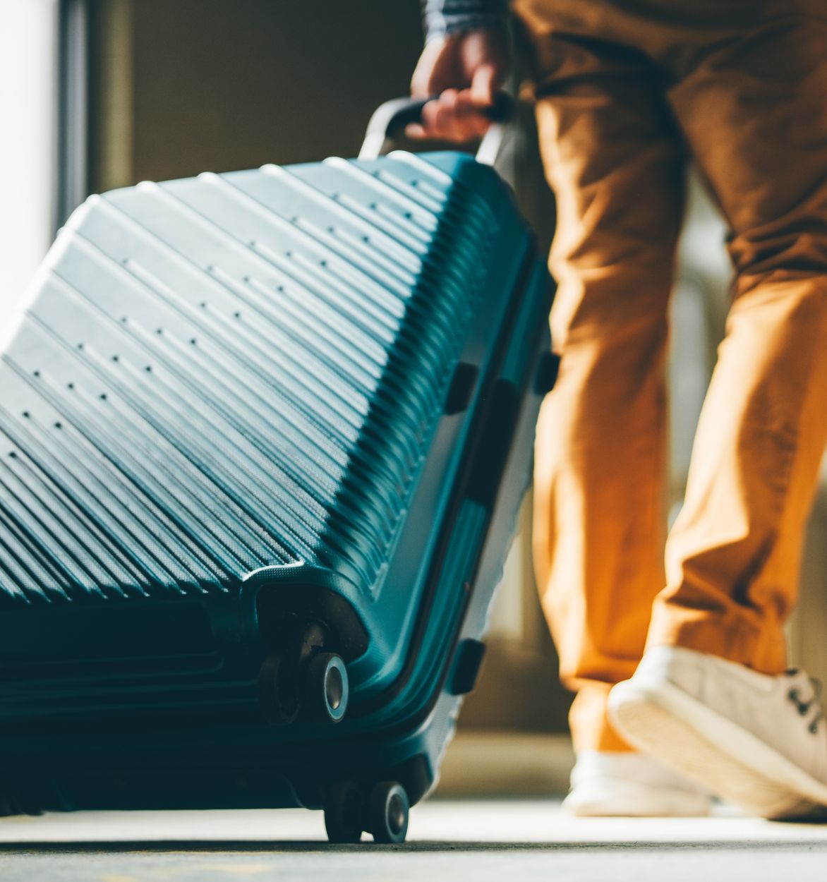 A low angle shot of a wheeled suitcase being pulled
