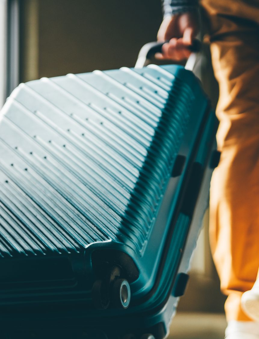 A low angle shot of a wheeled suitcase being pulled