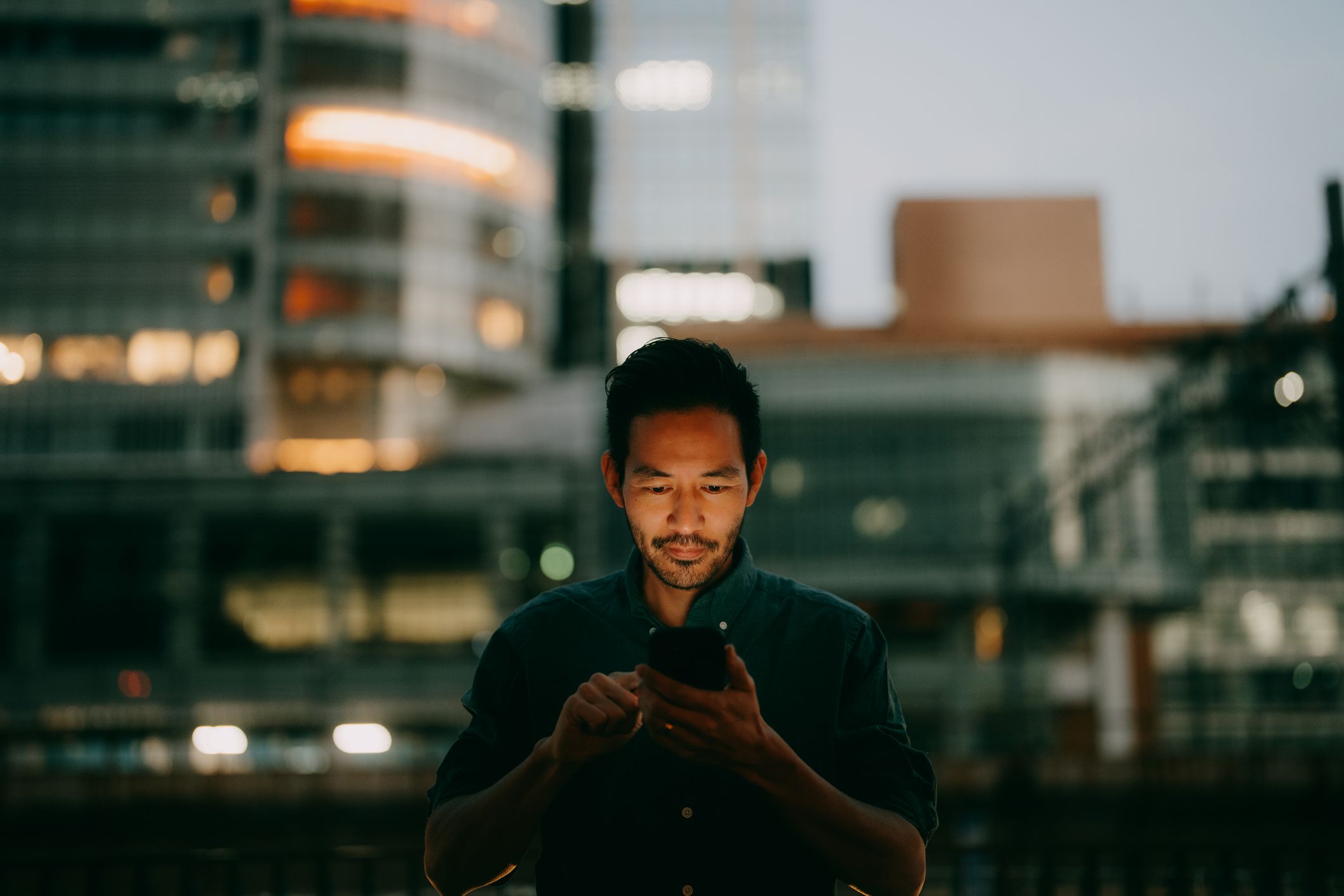 A businessman reading his phone in a city office