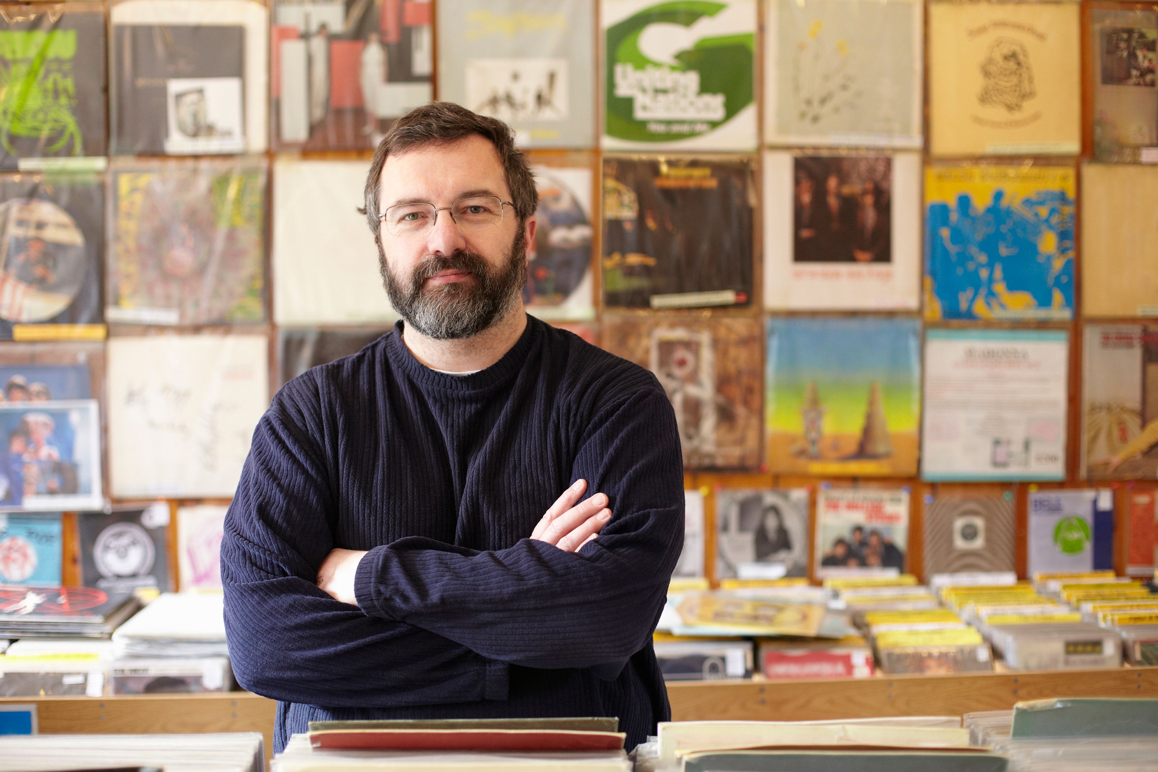 A contented early middle aged man stood in a record store