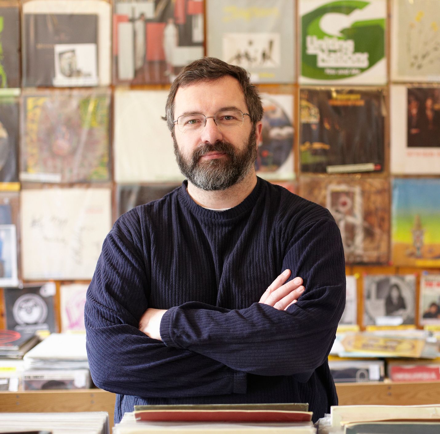 A contented early middle aged man stood in a record store