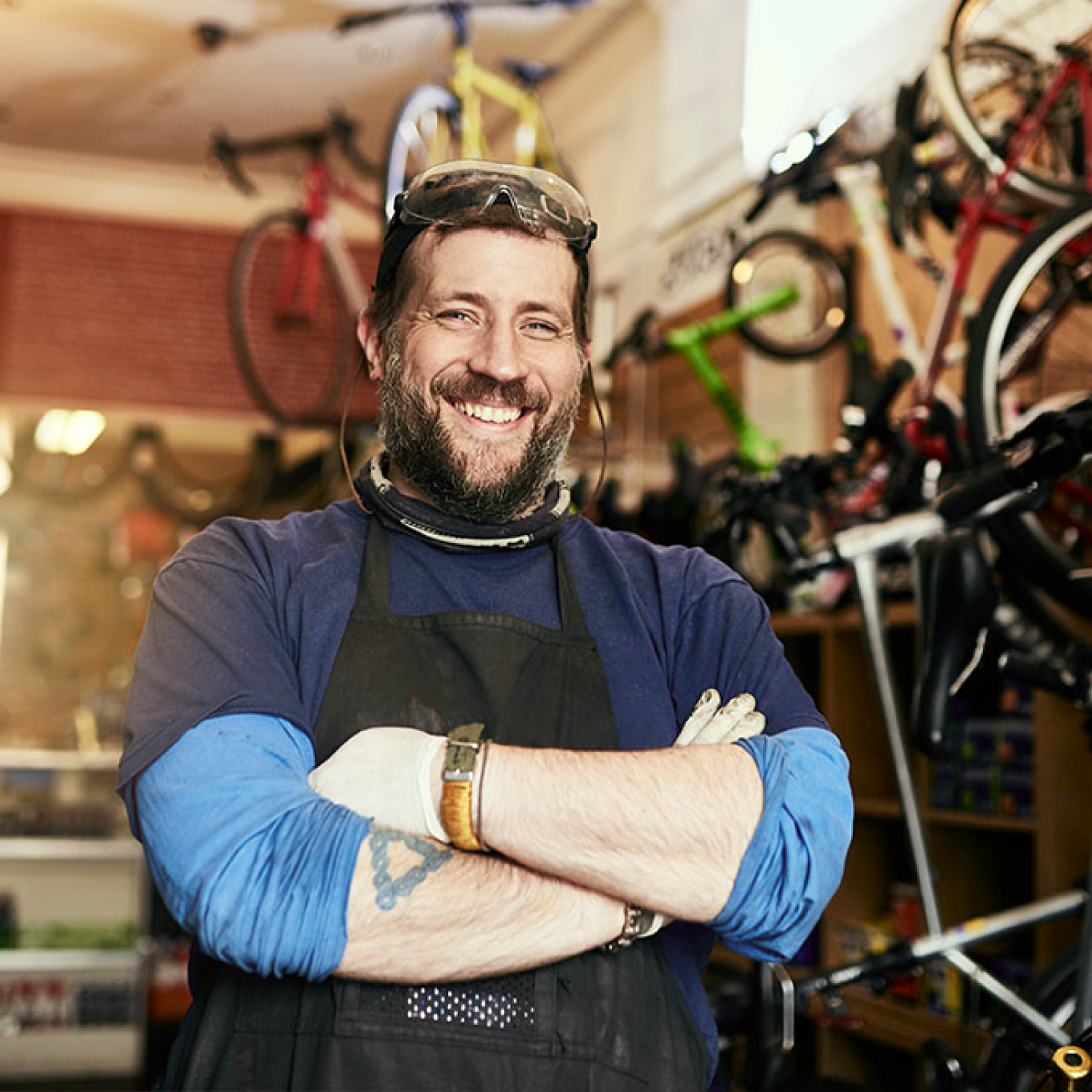 Man smiling while looking at the camera, arms crossed in a bike shop