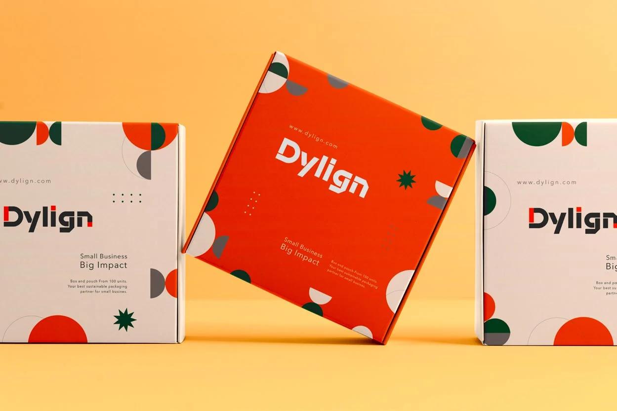An unbranded kraft stand-up pouch beside a plain folding carton on a neutral studio surface, lit from the upper left with soft contact shadows