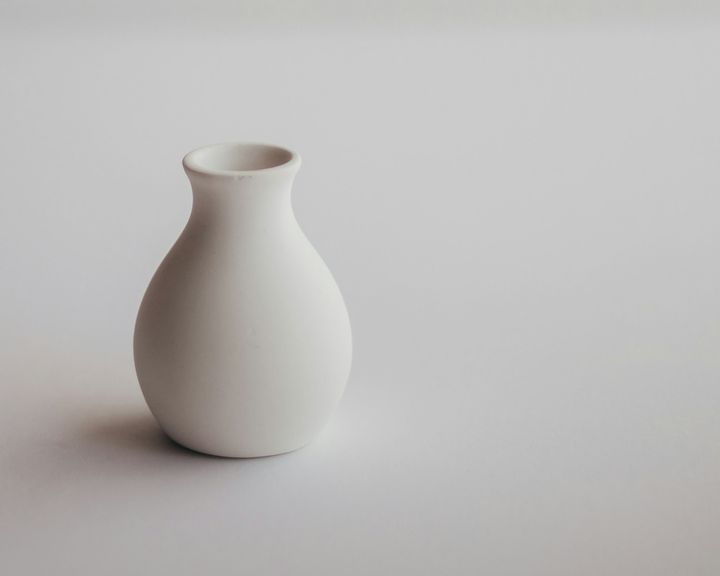 A white ceramic vase on a white surface, showing a soft contact shadow at its base and a single light direction.