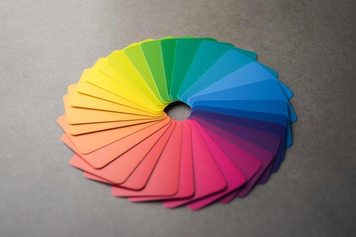 A fan of physical paint colour swatch cards arranged in a circle on a grey surface