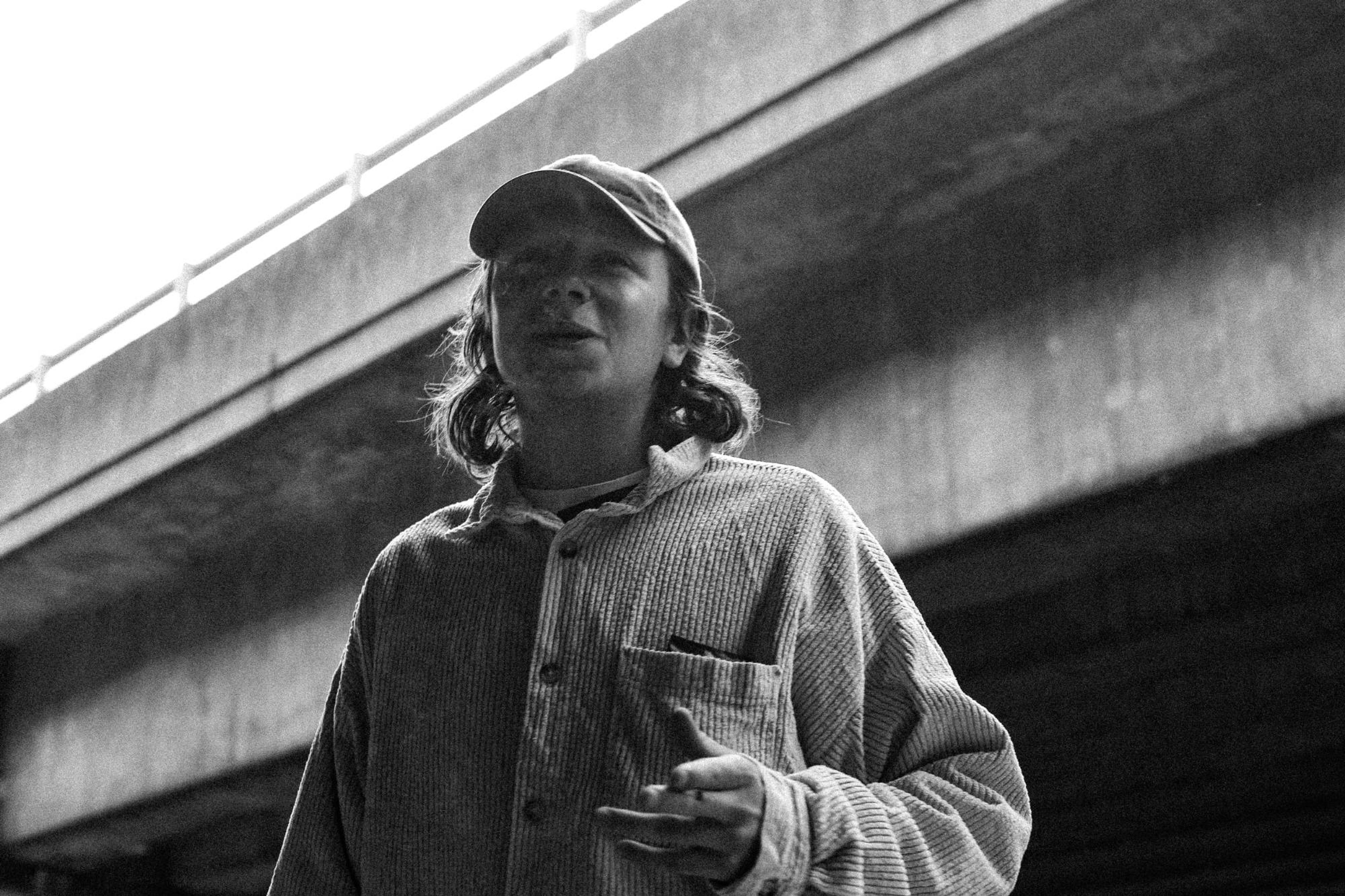 A crew member in a cap under a concrete flyover