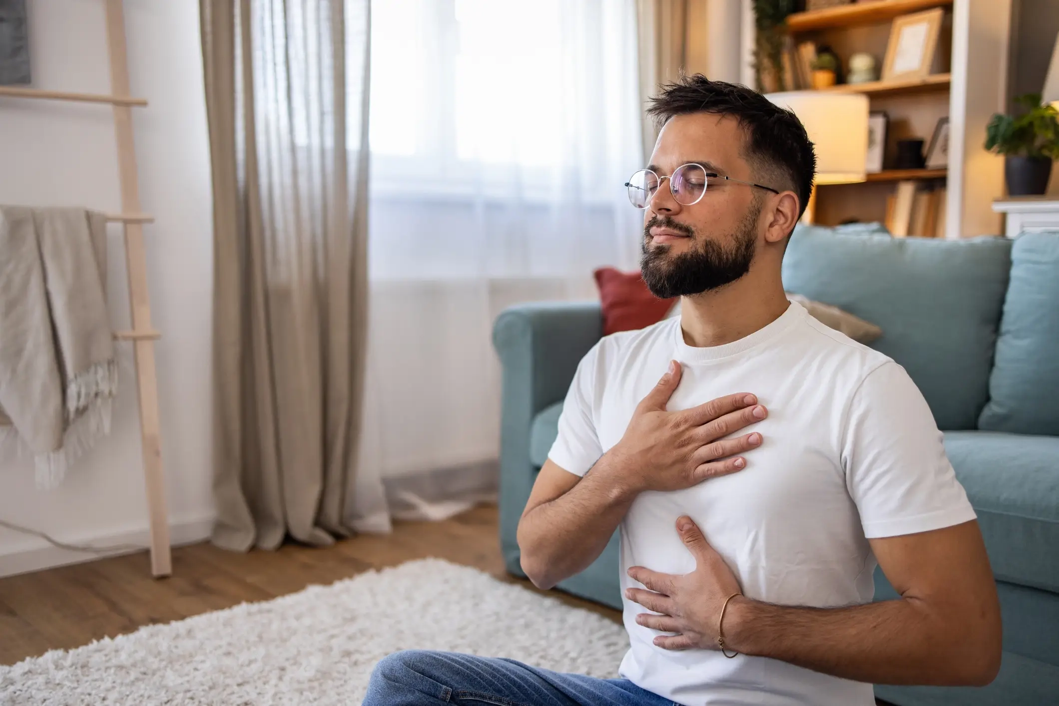 man sits with hand on chest relaxing 