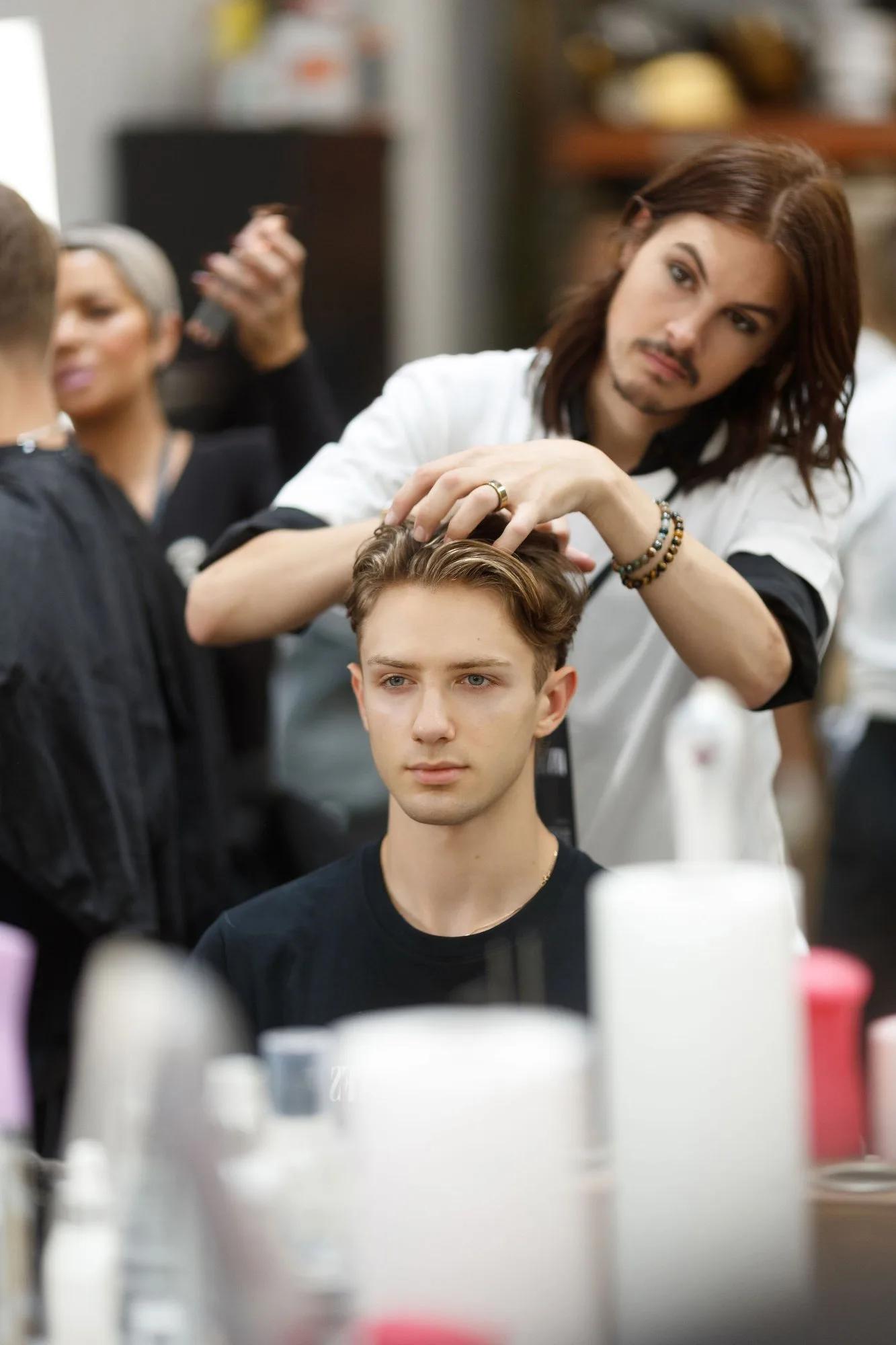 A stylist working on a participant’s hair backstage at YFS
