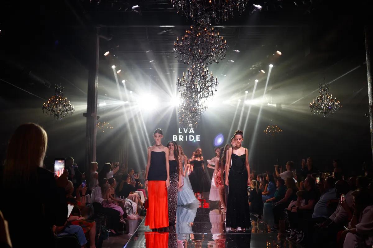 The LVA Bride runway at YFS, models in gowns under the lights, the brand on the screen behind