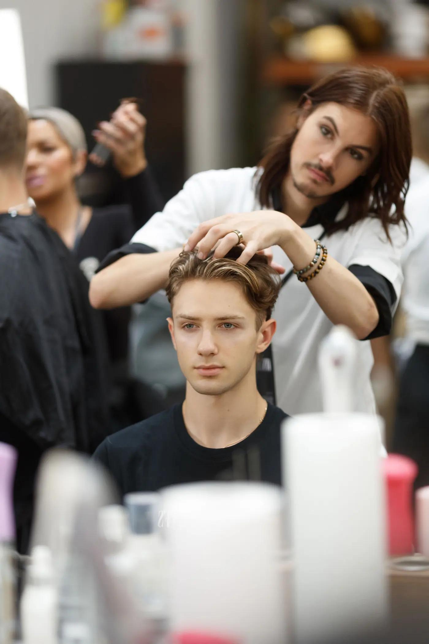 Hair stylist preparing a participant backstage