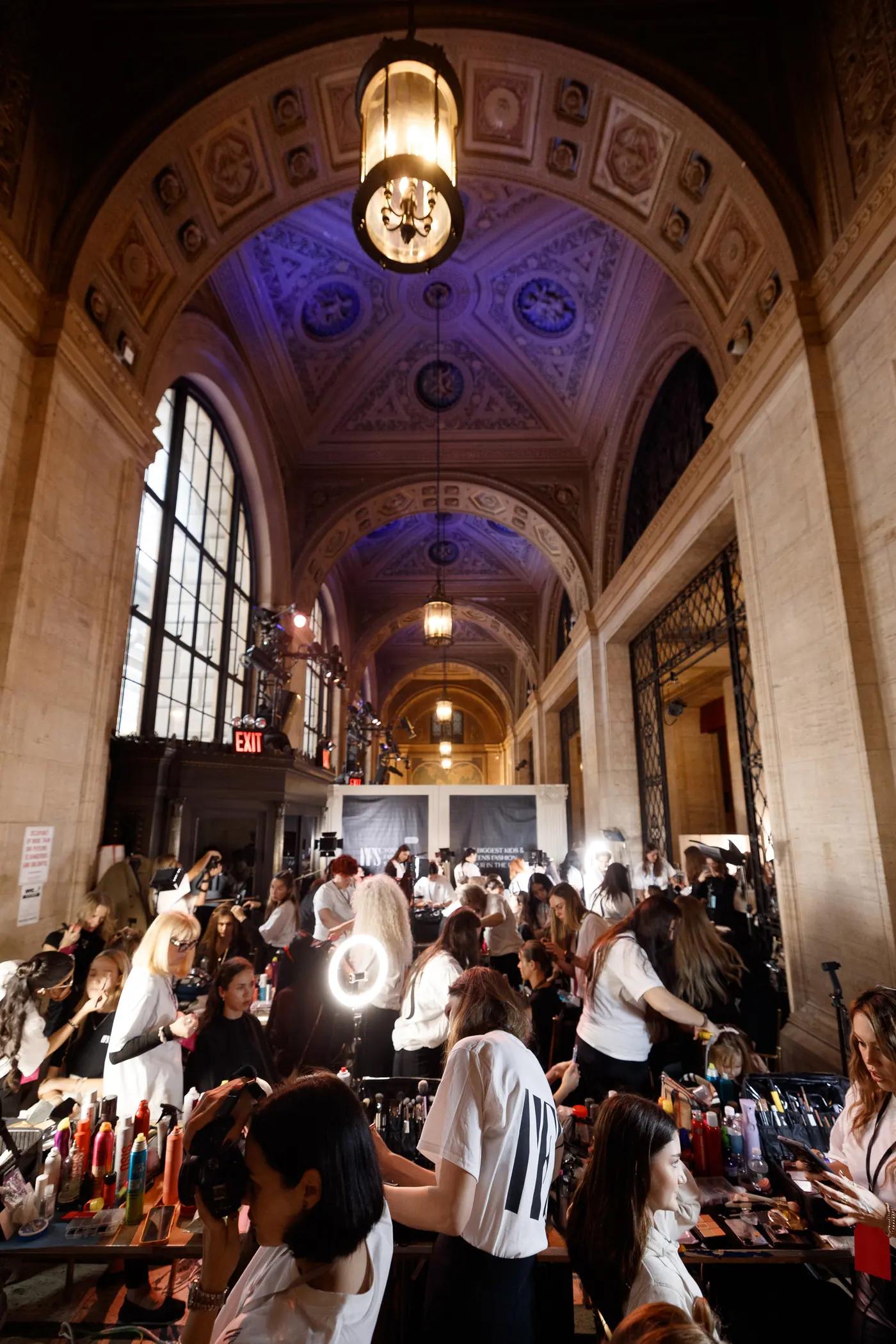 Participants and team backstage in a vaulted hall