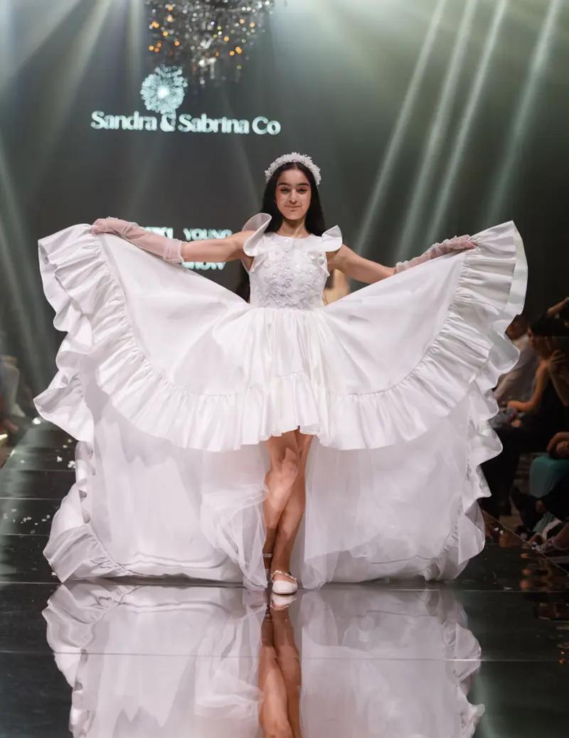 Girl in a white ruffled gown on the runway