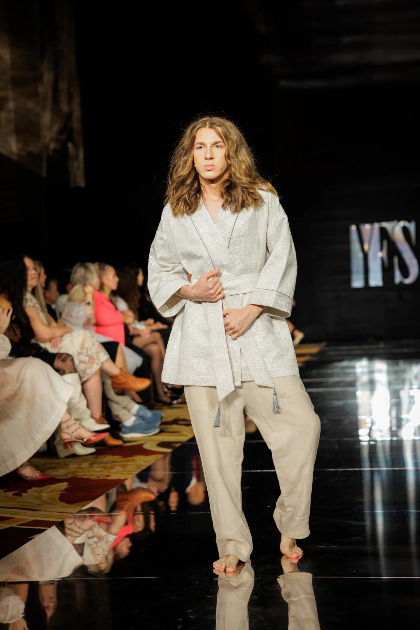 A male model in a white jacket and trousers on the YFS runway