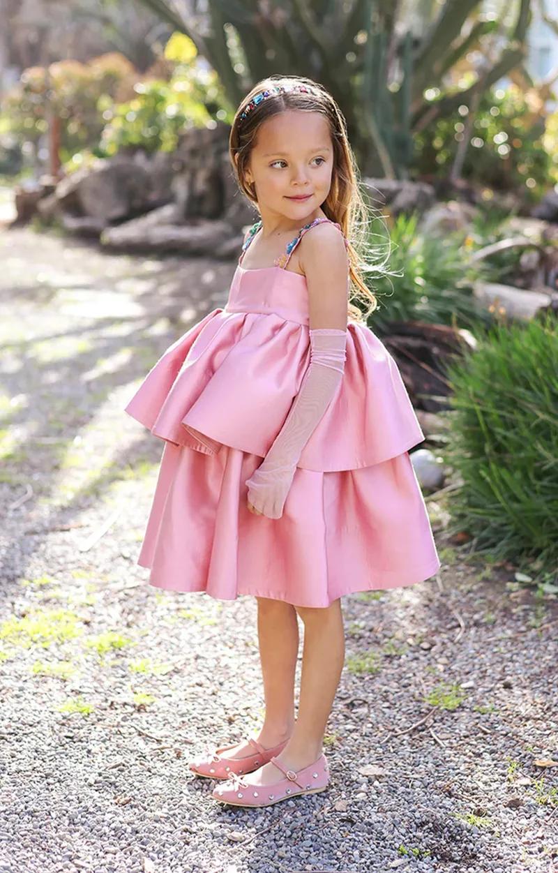 A girl in a pink tiered Lil Olives silk dress in a garden