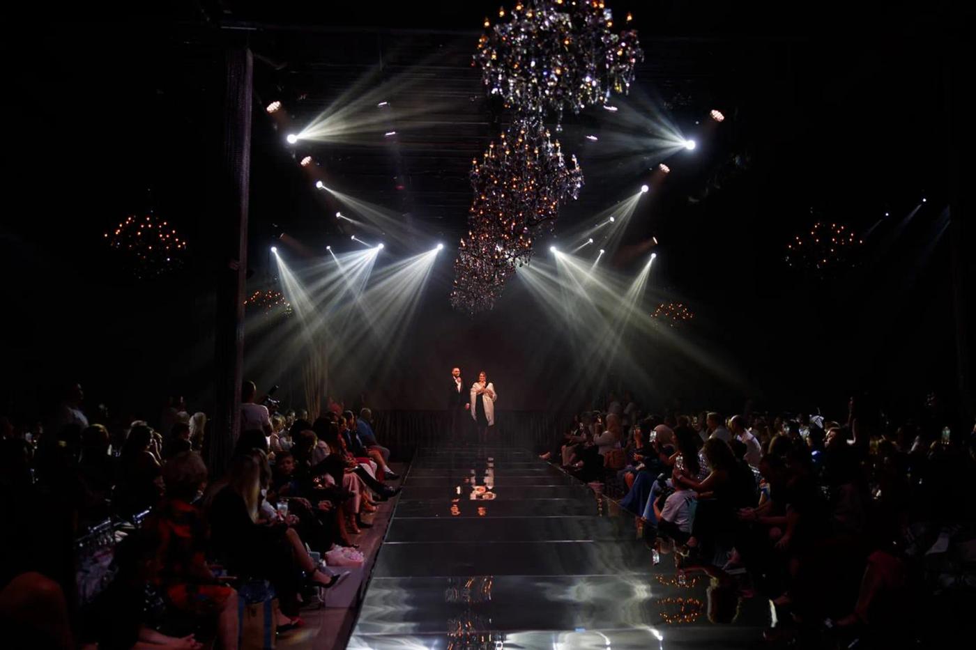 The YFS runway under chandeliers and stage lights, guests seated on both sides