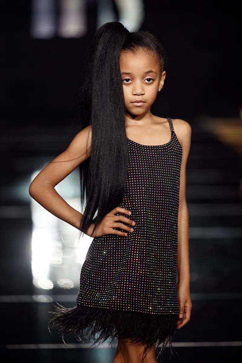 A girl in a black sequinned Milana Loren Couture dress with a feather hem on the YFS runway