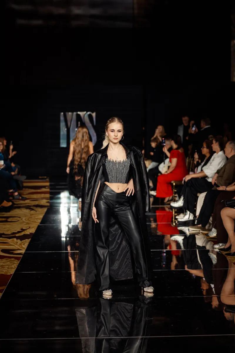A model in a black leather BUNDI coat, corset top and leather trousers on the YFS runway