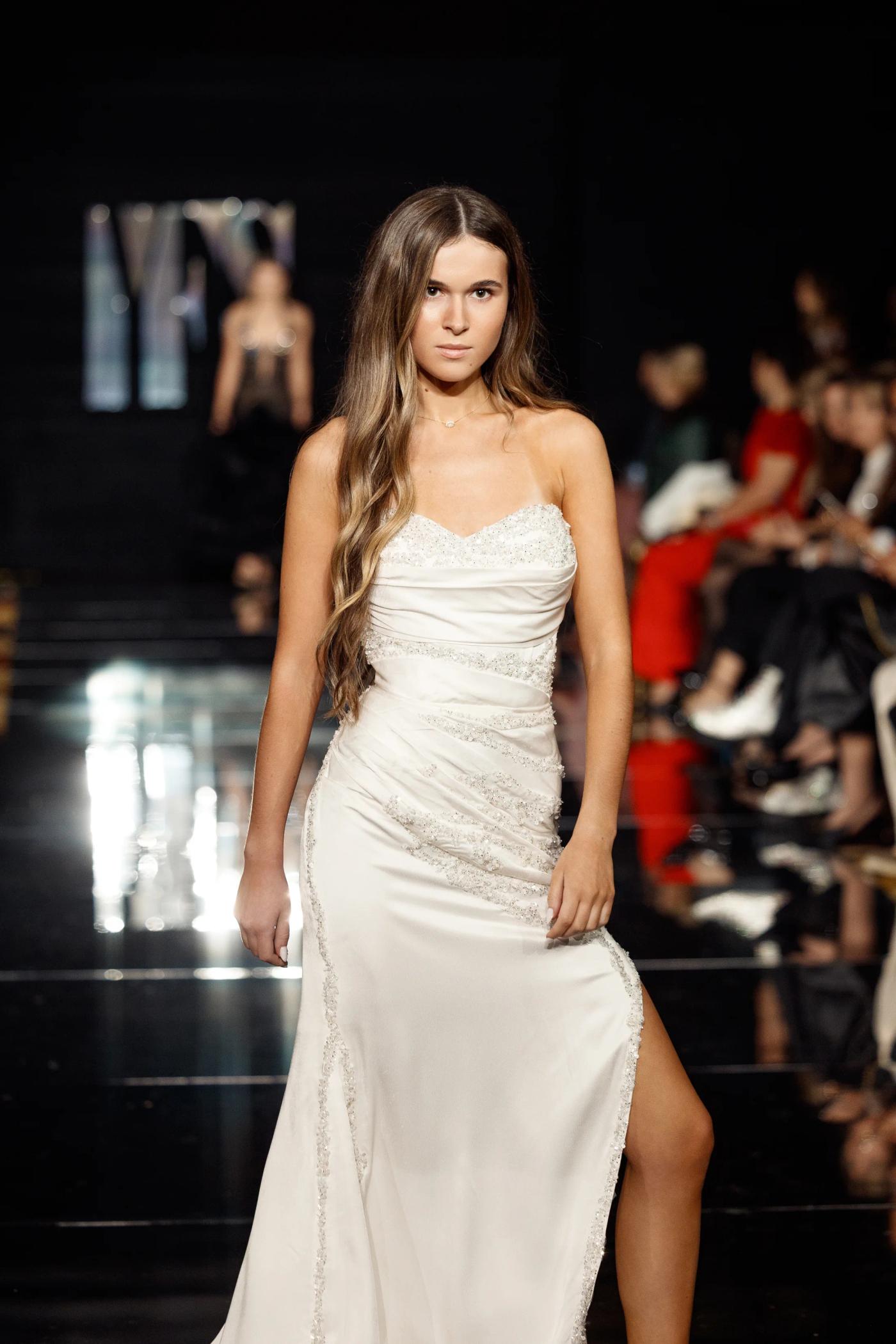 A model in a white satin slip gown on the YFS runway
